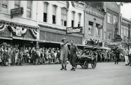 A parade in downtown Dallas in 1947 featuring parade floats, crowds, and the historic storefronts