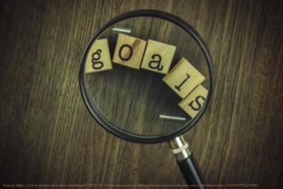 Image of magnifying glass over scrabble pieces spelling the word goals